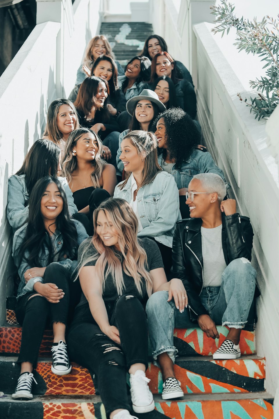 Diverse women smiling and chatting on colorful outdoor stairs.