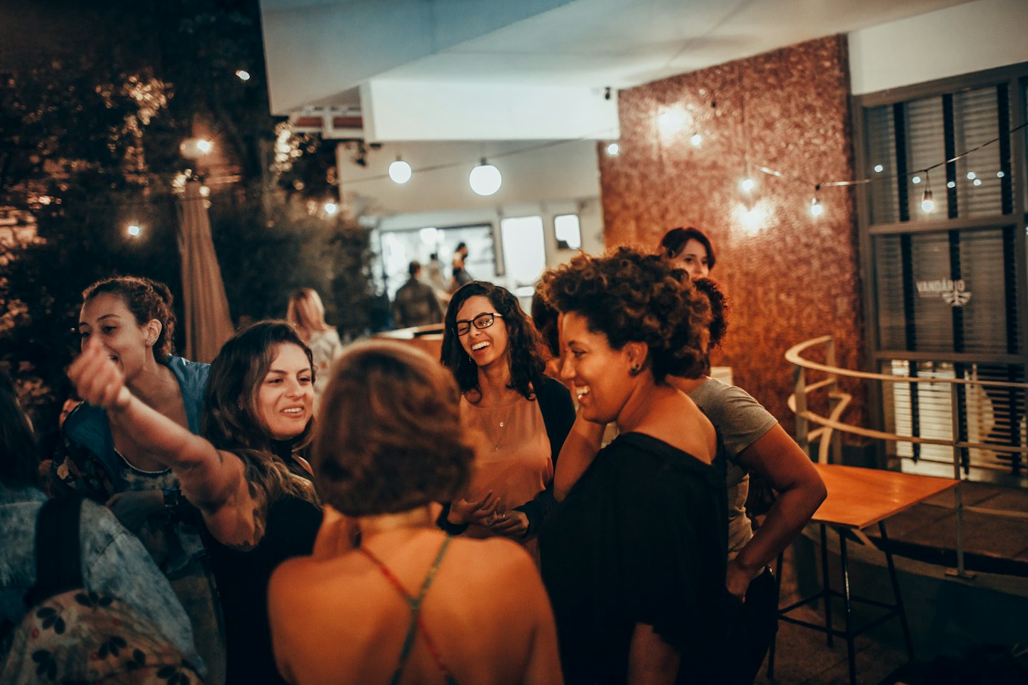 A group of women laughing and talking together at an outdoor gathering.