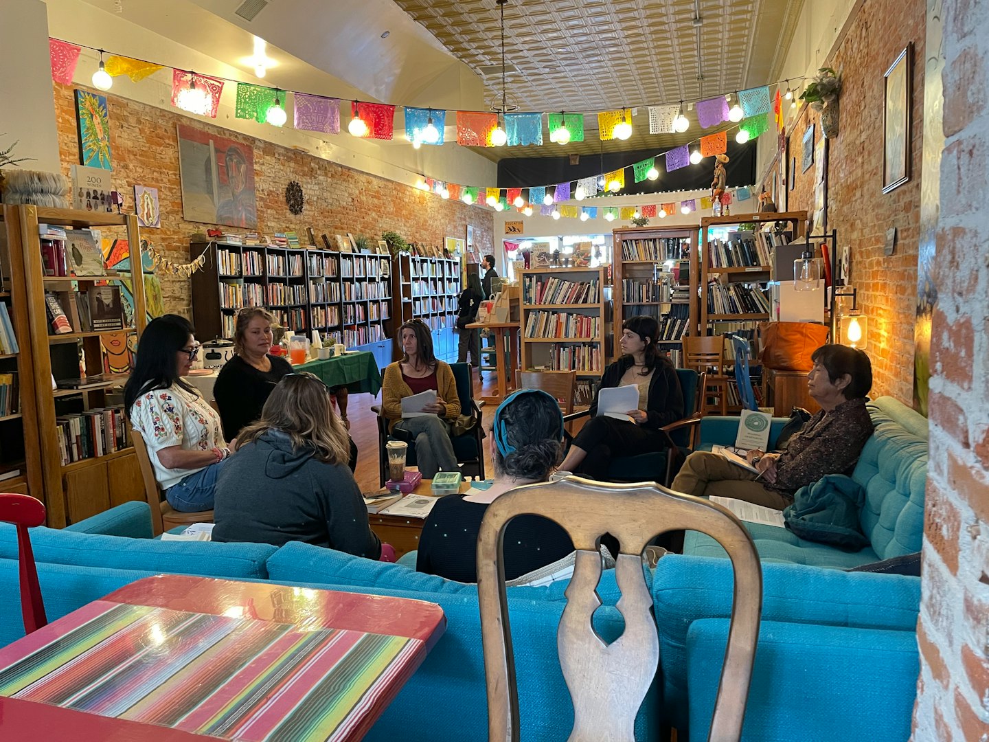 Women talk while sitting on furniture inside a bookstore.