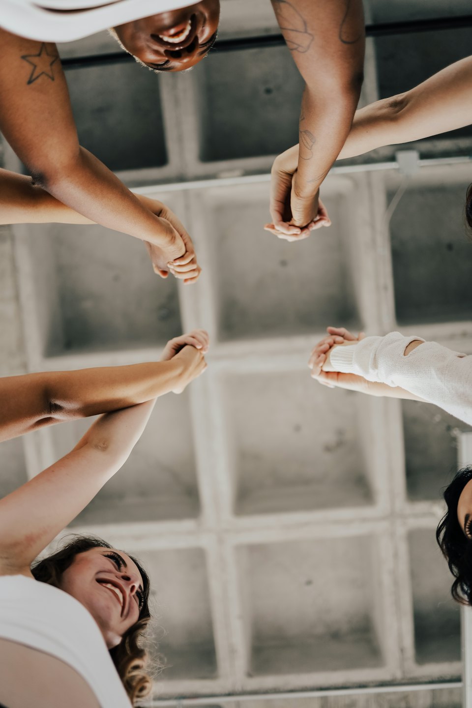 Diverse people holding hands in a circle showing unity and collaboration.
